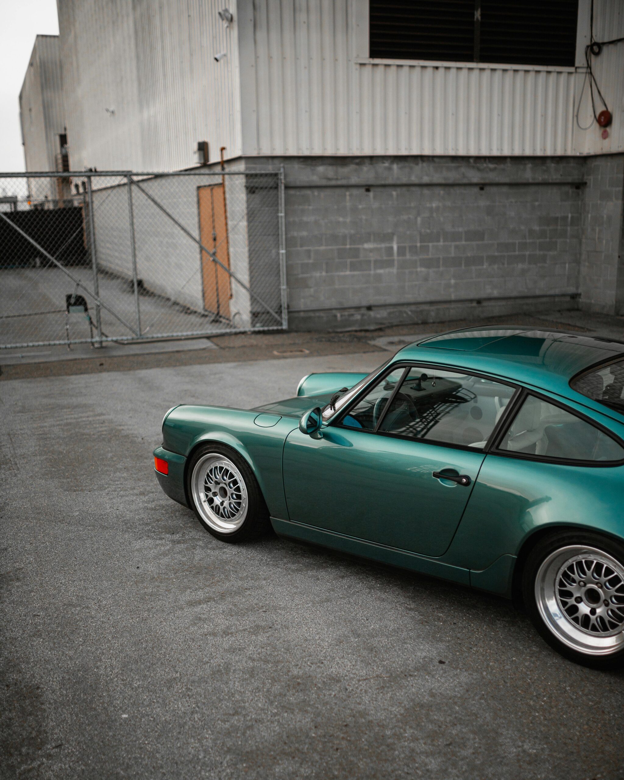 Classic green sports car parked in an industrial urban area.